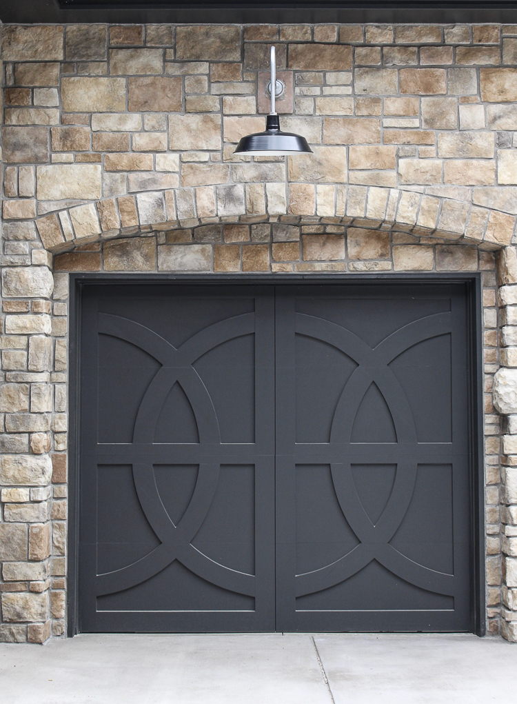 Modern Chateau Farmhouse style home with gooseneck lighting, black metal roof and custom european stone