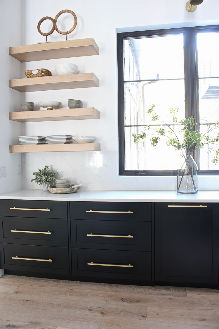 White oak floating shelves in kitchen with lower black cabinets