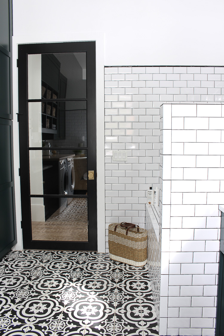 laundry room with dark green cabinets and black and white patterned tile