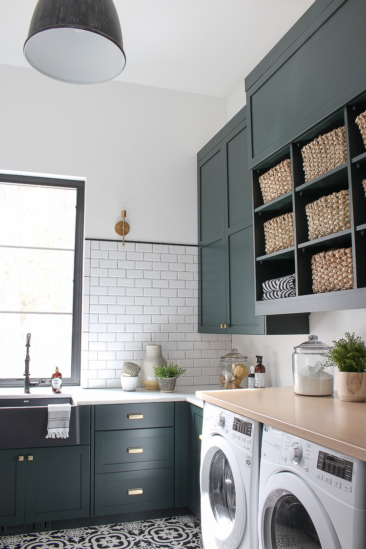 black-white-laundry-room-beveled-subway-tile-patterned-floor-dark-green-cabinets-natural-wood-gold-hardware